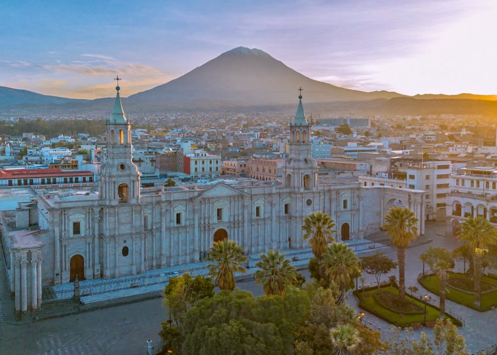 Drone shot of Arequipa's cathedral with El Misti volcano in the background at sunset.